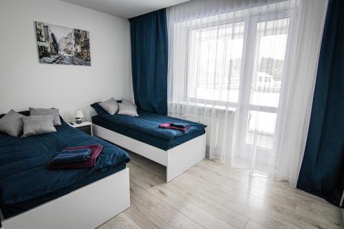 1 dormitorio con 2 camas y ventana en Ramūs apartamentai, en Anykščiai