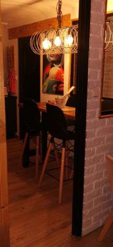 a dining room table with two chairs and a chandelier at Gîtes déco pop et chaleureuse avec jacuzzi, sauna, piece coquine in Calais