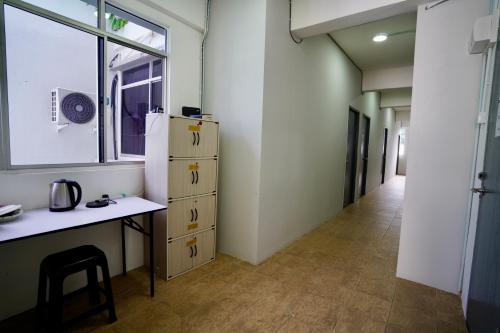 a room with a desk and a refrigerator and a hallway at Swanling Kuching in Kuching