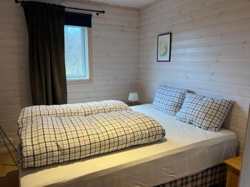 1 dormitorio con 1 cama con 2 almohadas y ventana en Feriehus med ti senger på Skaidi, en Hammerfest