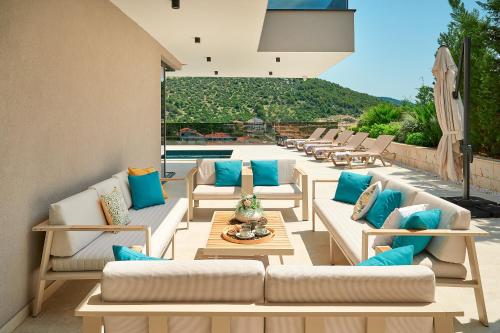 a patio with white couches and blue pillows at Villas Lucy - 1 Lemon -outdoor pool , 2 Cherry-indoor pool and 3 Plum-outdoor pool in Marina