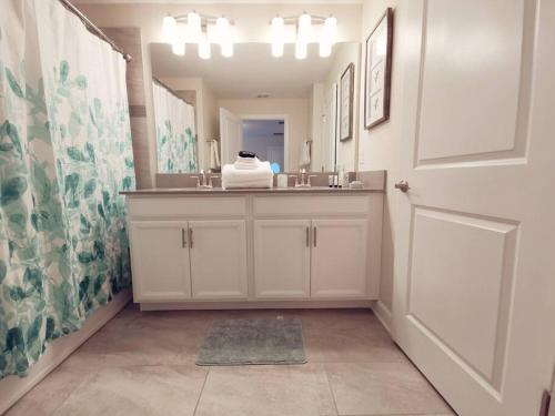 een badkamer met een wastafel en een spiegel bij Makin Memories Gated Resort Style Community Storey Lake in Kissimmee