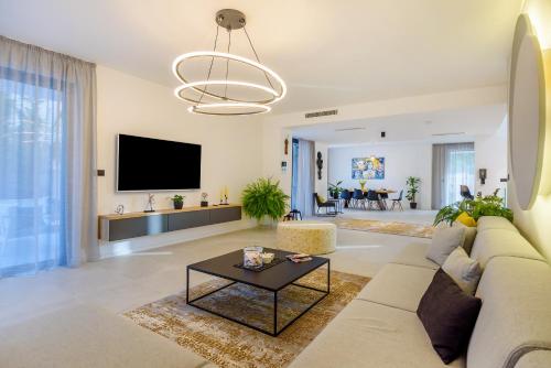 a living room with a couch and a tv at Villas Lucy - 1 Lemon -outdoor pool , 2 Cherry-indoor pool and 3 Plum-outdoor pool in Marina