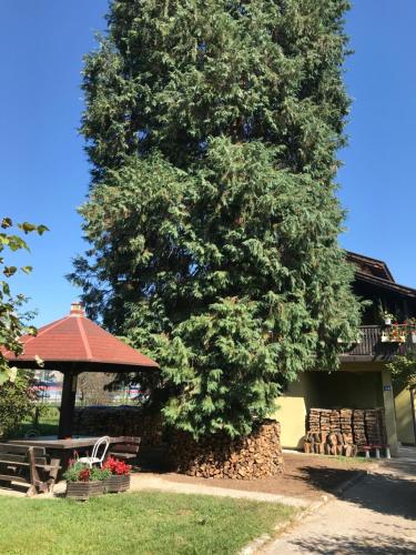 a large tree next to a gazebo and a picnic table at Garden's apartman - Kosjerić in Kosjerić