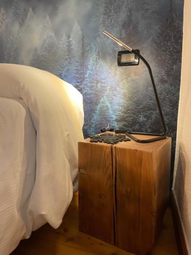 a lamp on a wooden night stand next to a bed at La Chambre des Rêves in Aosta
