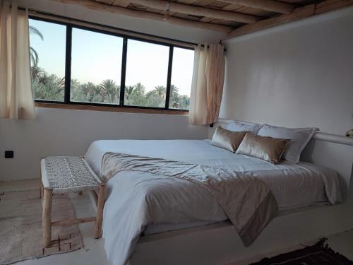 a white bedroom with a large bed and a window at Hôte sahara & spa TADIGHOUST in El Hara