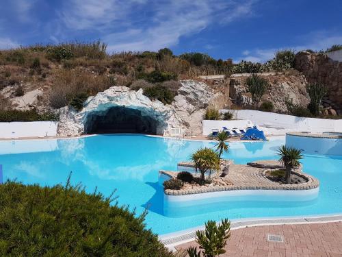 een groot zwembad met blauw water in een resort bij Charme Suite B&B Experience in Santa Teresa Gallura