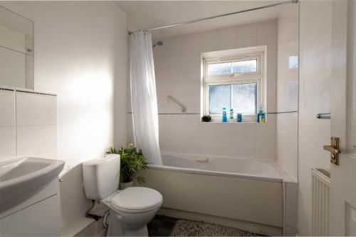 uma casa de banho branca com um WC, uma banheira e um lavatório. em Cosy Retreat - SmartTV and Wi-Fi em Gillingham