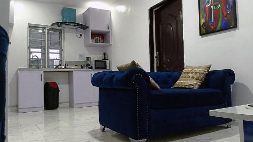 ein blaues Sofa im Wohnzimmer mit Küche in der Unterkunft JKA1-Bedroom Luxury Serviced Apartment in Lagos