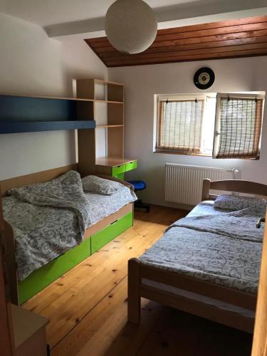 two beds in a bedroom with wooden floors and windows at Garden's apartman - Kosjerić in Kosjerić