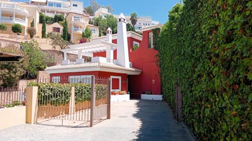 a red house with a gate in front of a hedge at Casa Roja in Almuñécar