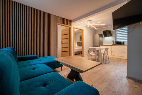 a living room with a blue couch and a table at Zielony Zakątek Karpacz Apartamenty in Karpacz