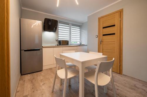 a kitchen with a white table and chairs and a refrigerator at Zielony Zakątek Karpacz Apartamenty in Karpacz
