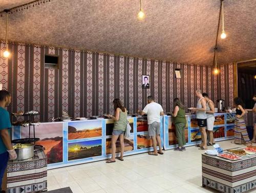 Un groupe de personnes autour d'un comptoir alimentaire dans l'établissement Miral Night Camp, à Wadi Rum