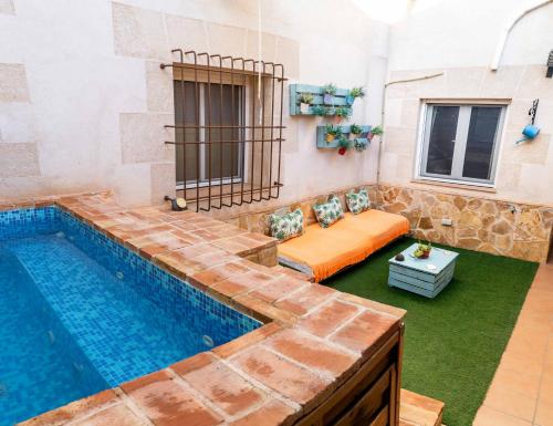 a pool in a room with a bed next to a swimming pool at La Posada de Dulcinea in Mota del Cuervo