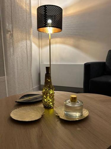 a table with a lamp and plates and a glass jar at Apt Évreux 900m de la gare in Évreux