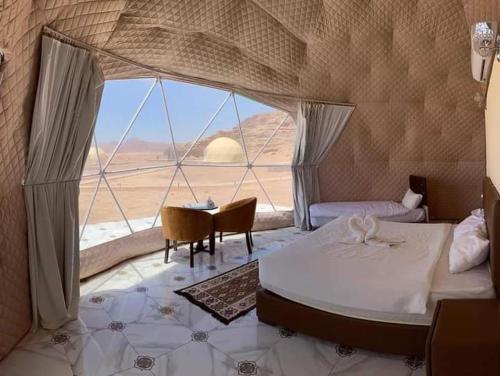 a room with a bed and a table and a window at Miral Night Camp in Wadi Rum