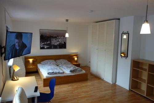a bedroom with a bed and a desk and a tv at Geräumige Ferienwohnung in ruhiger Lage in Rheinstetten