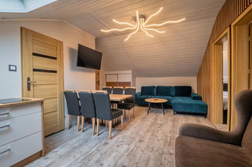 a living room with a couch and a table and chairs at Zielony Zakątek Karpacz Apartamenty in Karpacz