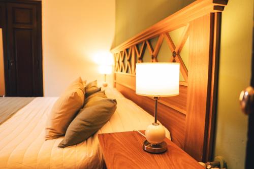 um quarto com uma cama com um candeeiro sobre uma mesa em HOSTAL CRUZ CHICA em La Cumbre