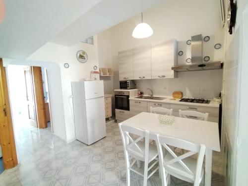 a kitchen with a table and a white refrigerator at Ischia Ponte romantic apartment in the historical center and near the sea in Ischia