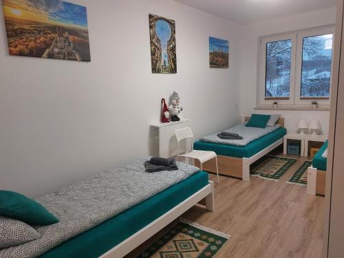 a bedroom with two beds and a table and two windows at Apartament Zagórze, bezpłatny ogrodzony parking, Netflix in Kielce