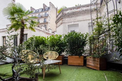 eine Terrasse mit Pflanzen, einem Tisch und Stühlen in der Unterkunft Hôtel Des Batignolles in Paris