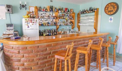 a bar with wooden chairs and a brick wall at Hotel Rocas del Pacifico in Pichilemu