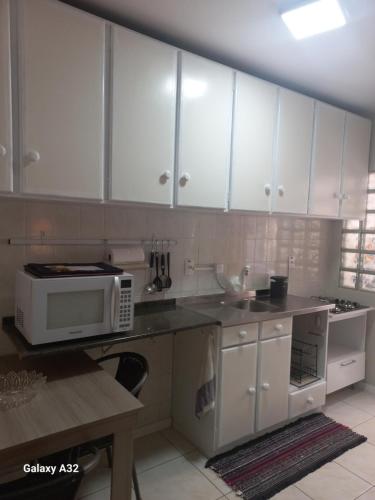 cocina con armarios blancos y microondas en Apto111consuladoamericano en Porto Alegre