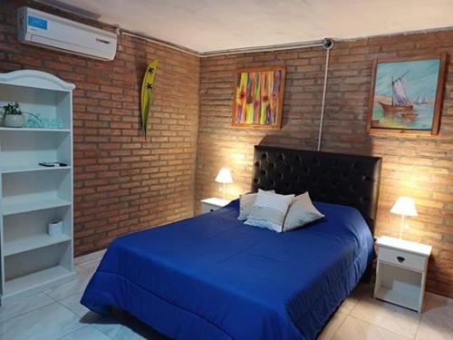 Un dormitorio con una cama azul y una pared de ladrillo en Costa Dorada en San Antonio de Arredondo
