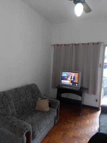 a living room with a couch and a tv at Apartamento MOBILIADO 2 QUARTOS in Volta Redonda