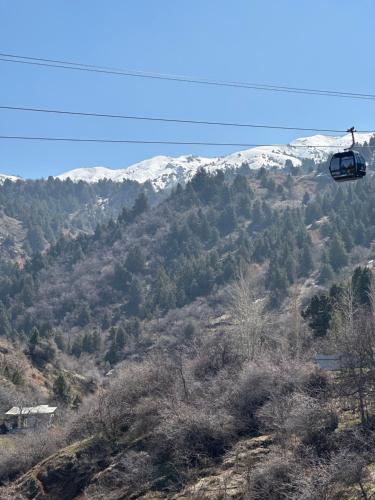 a ski lift flying over a mountain with snow covered mountains at Amirsoy Apple Dacha in Chimgan