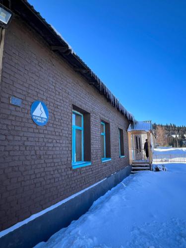 a person standing outside of a brick building in the snow at Beymaral Lodge Jyrgalan in Dzhergalan