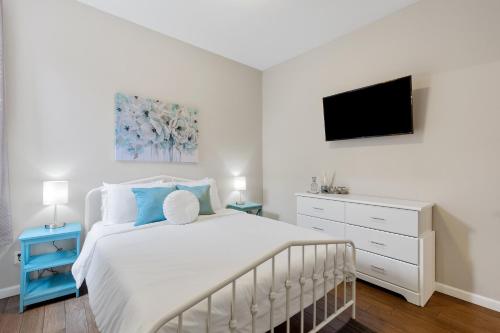 1 dormitorio con 1 cama blanca y TV en Exquisitely Designed Townhome - JZ Vacation Rentals en St. Louis