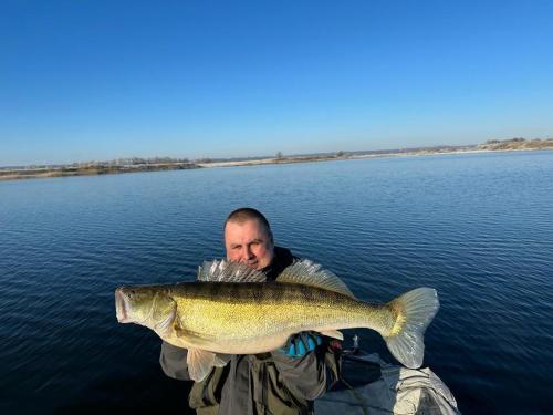 a man holding a large fish in the water at Noclegi Little Sheep in Chojna