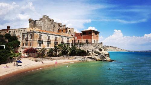 un edificio su una spiaggia con persone in acqua di Appartamento Porto Marina S G 2 a Licata