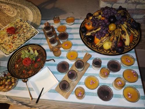a table with plates of food and fruit on it at Hôte sahara & spa TADIGHOUST in El Hara