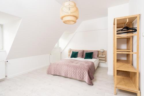 Dormitorio blanco con cama y estante de libros en Apartament Starówka by RENT4YOU, en Olsztyn