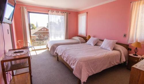a bedroom with two beds and a large window at Hotel Rocas del Pacifico in Pichilemu