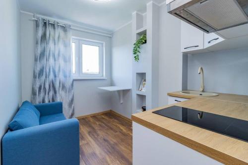 a living room with a blue couch and a kitchen at Studio flat in Tallinn