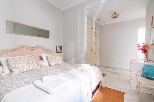 een witte slaapkamer met een groot bed en een stoel bij San Lorenzo en Esencia in Sevilla