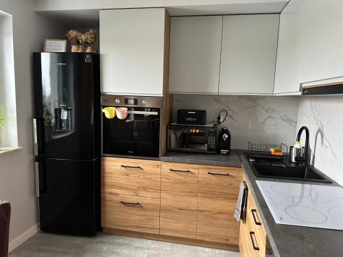 a kitchen with a black refrigerator and wooden cabinets at Apartament z widokiem in Chełm