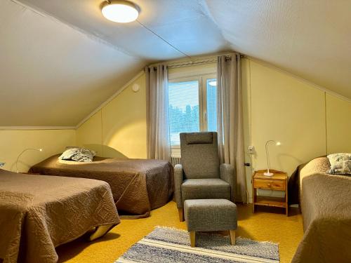 um quarto com duas camas e uma cadeira e uma janela em Chalet Mummola em Naamijoki