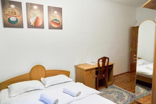 1 Schlafzimmer mit 2 Betten, einem Schreibtisch und einem Spiegel in der Unterkunft Sweet Vibe Home in Almaty