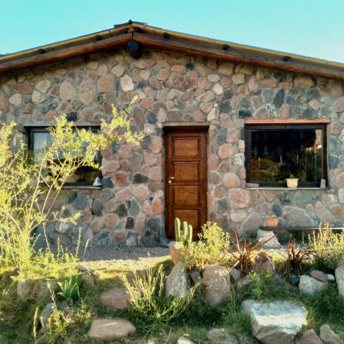 Casa de piedra con puerta de madera y ventana en Refugio de Montaña "Casa Chakana " en Luján de Cuyo