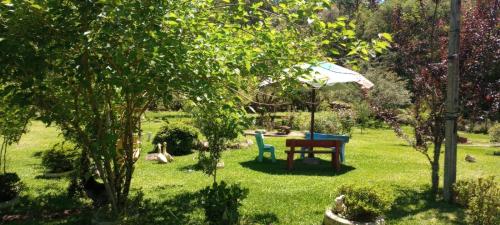 um jardim com uma mesa e cadeiras e um guarda-sol em Cabanas Brocker em Gramado