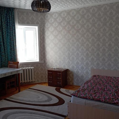 a bedroom with a bed and a window and a rug at Канышай in Osh