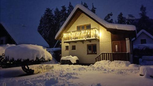 a house with a lighted balcony in the snow at night at Chata Mareček - v lesní osadě u řeky Lužnice in Skalice