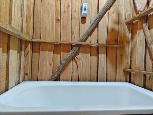 een bad in een kamer met een houten muur bij Cabaña De Montaña in Aguas Claras