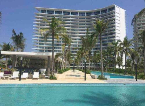 un grand bâtiment avec des palmiers et une piscine dans l'établissement Peninsula Ixtapa 5 bedrooms, à Ixtapa